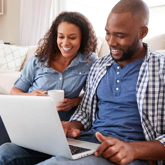 Man and Woman Sitting on a Couch Looking at a Laptop Computer