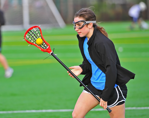 girl playing lacrosse while wearing eye safety googles